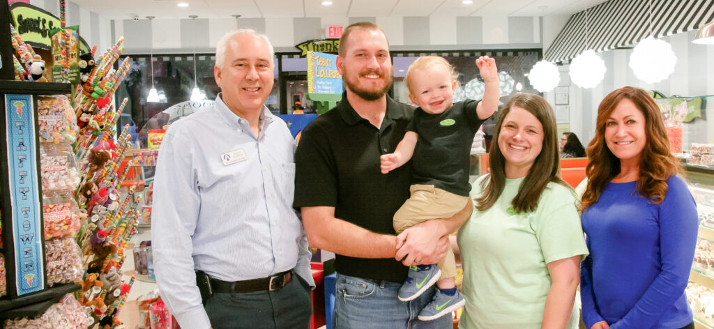 Small business owners and family members posing inside a retail store for professional branding and marketing photography.