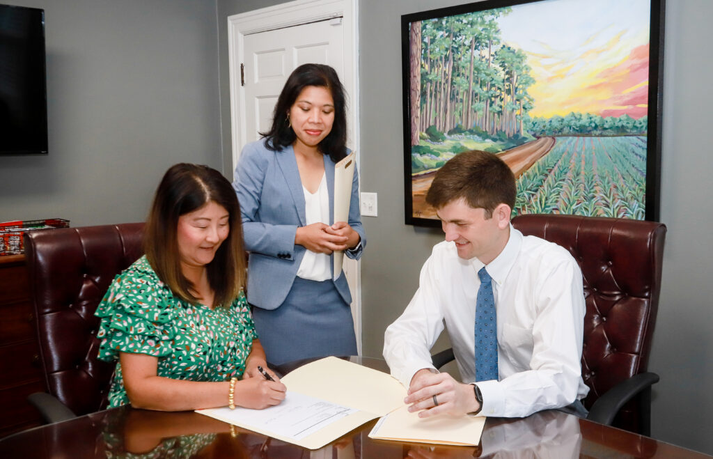 Business owners reviewing and signing documents during a professional consultation meeting, representing marketing strategy and business support services in Georgia.